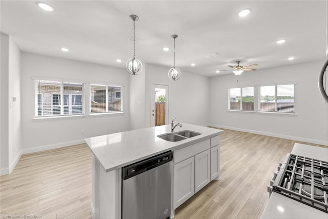 kitchen with a wealth of natural light, a center island with sink, sink, and dishwasher