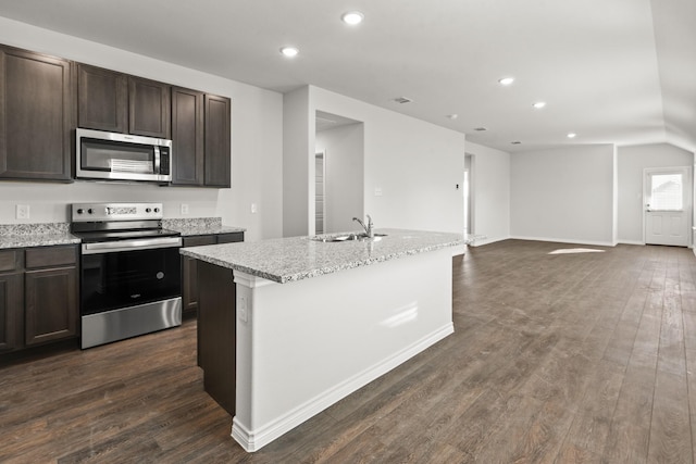 kitchen with a center island with sink, stainless steel appliances, dark wood-type flooring, light stone counters, and sink