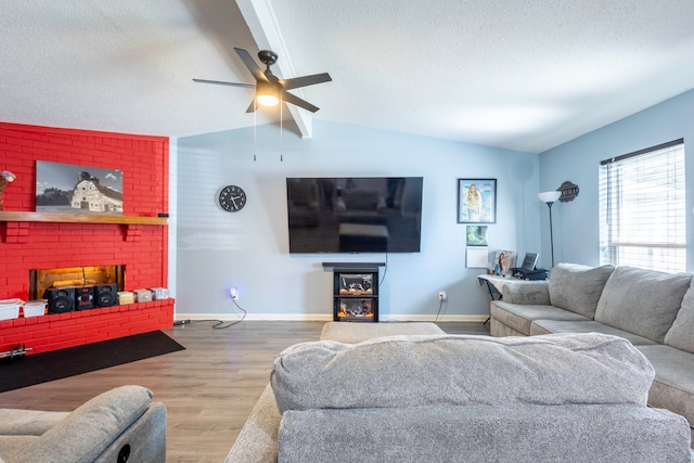 living room with ceiling fan, a textured ceiling, hardwood / wood-style flooring, a brick fireplace, and vaulted ceiling