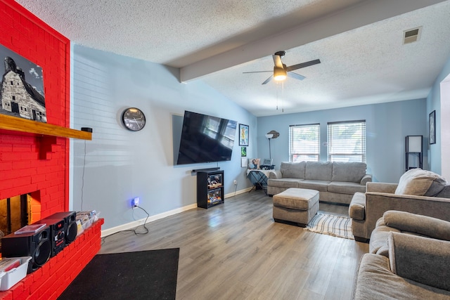 living room featuring ceiling fan, a textured ceiling, wood-type flooring, a fireplace, and lofted ceiling with beams