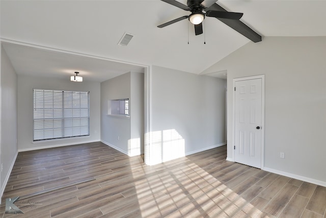 spare room featuring light hardwood / wood-style floors, lofted ceiling with beams, and ceiling fan