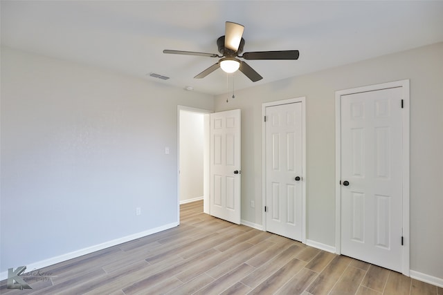 unfurnished bedroom with ceiling fan, multiple closets, and light wood-type flooring