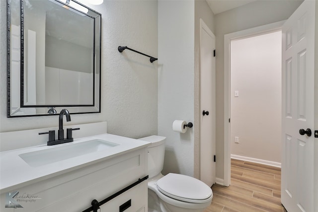 bathroom featuring vanity, hardwood / wood-style flooring, and toilet