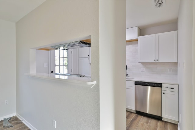 kitchen with white cabinetry, light hardwood / wood-style floors, decorative backsplash, and dishwasher