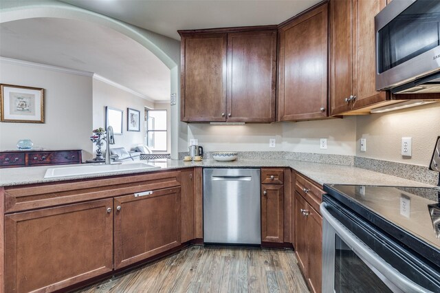 kitchen featuring sink, wood-type flooring, light stone countertops, and appliances with stainless steel finishes