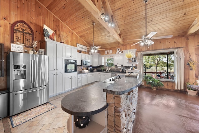 kitchen featuring tasteful backsplash, dark countertops, a ceiling fan, wooden walls, and appliances with stainless steel finishes