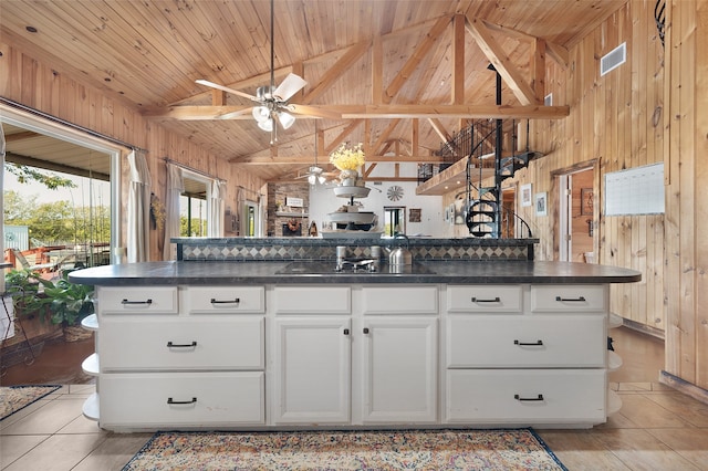 kitchen with wood walls, light tile patterned floors, and white cabinets