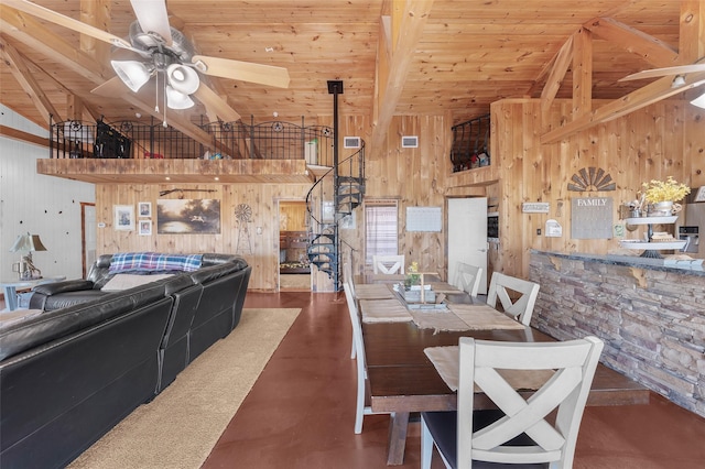 dining space featuring ceiling fan, beamed ceiling, and wooden walls