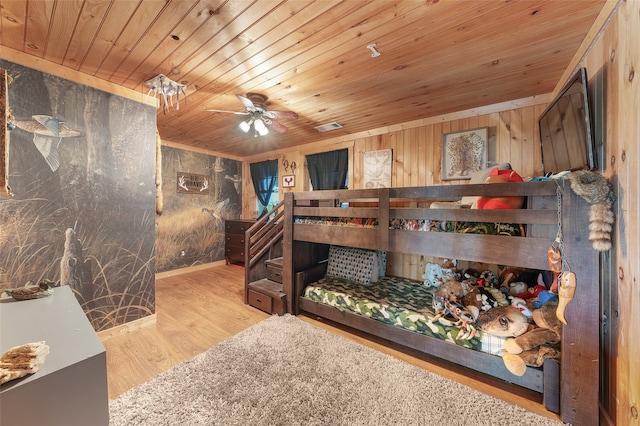 bedroom featuring wood ceiling, wooden walls, light wood-type flooring, and ceiling fan