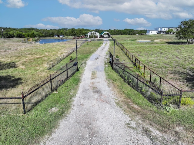 view of road featuring driveway, a rural view, and a gated entry