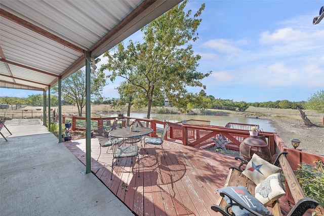 wooden terrace featuring outdoor dining space and a water view