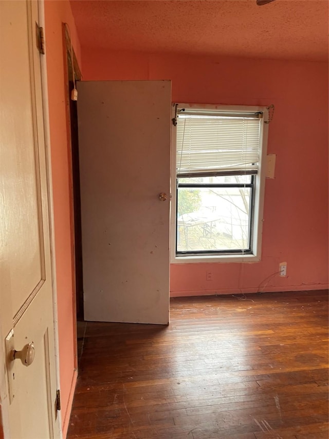 unfurnished room with dark wood-type flooring and a textured ceiling