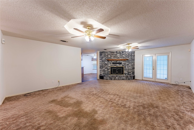 unfurnished living room with carpet, ceiling fan, a textured ceiling, and a brick fireplace