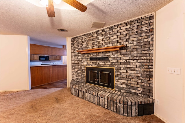 1490 Farm Rd Unit 2120, Clarksville, TX 75426 - unfurnished living room with a textured ceiling, ceiling fan, a brick fireplace, carpet flooring, and visible vents