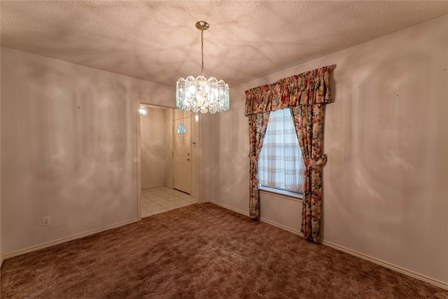 carpeted empty room with a notable chandelier and a textured ceiling