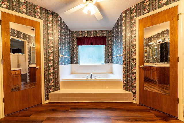 bathroom featuring vanity, a relaxing tiled tub, a textured ceiling, and hardwood / wood-style floors