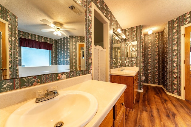 1490 Farm Rd Unit 2120, Clarksville, TX 75426 - bathroom featuring wallpapered walls, wood finished floors, a sink, and a textured ceiling