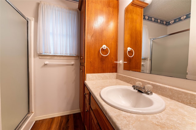 bathroom with a shower with door, vanity, a textured ceiling, and wood-type flooring