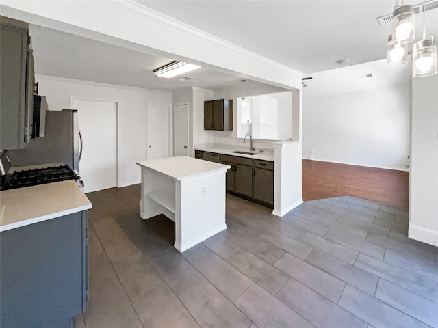 kitchen featuring sink, a kitchen island, hardwood / wood-style floors, pendant lighting, and gas range