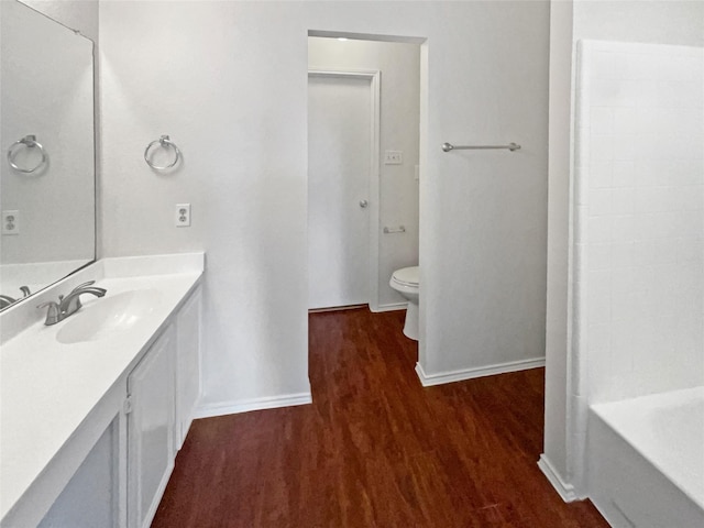 5103 Whitehaven Dr, Garland, TX 75043 - bathroom with wood finished floors, baseboards, toilet, a bathtub, and vanity