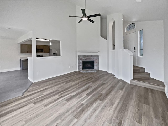 5103 Whitehaven Dr, Garland, TX 75043 - unfurnished living room featuring wood finished floors, high vaulted ceiling, a brick fireplace, a ceiling fan, and stairs