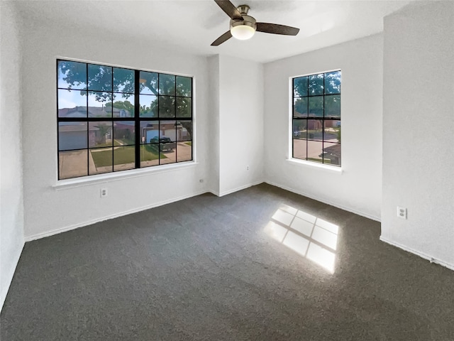 empty room with dark colored carpet and ceiling fan