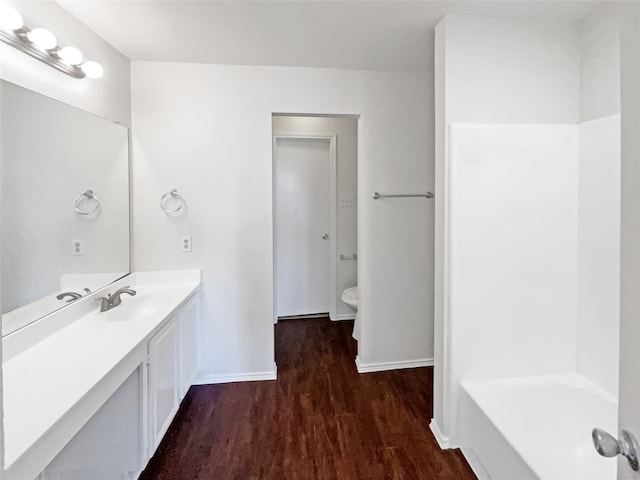 bathroom featuring a bath, toilet, vanity, and hardwood / wood-style floors