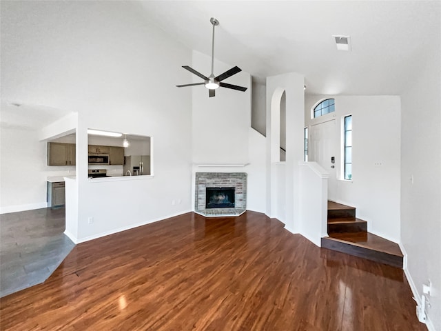 unfurnished living room with ceiling fan, high vaulted ceiling, dark hardwood / wood-style flooring, and a fireplace