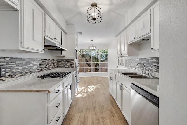 kitchen with white cabinets, appliances with stainless steel finishes, an inviting chandelier, and pendant lighting