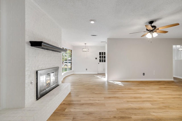 unfurnished living room featuring ceiling fan, a textured ceiling, a fireplace, and light hardwood / wood-style flooring