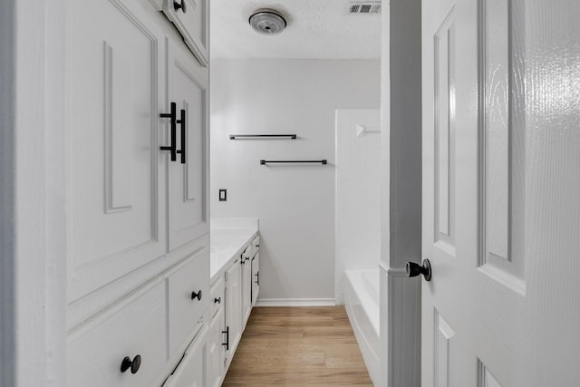 bathroom featuring shower / bath combination, wood-type flooring, vanity, and a textured ceiling