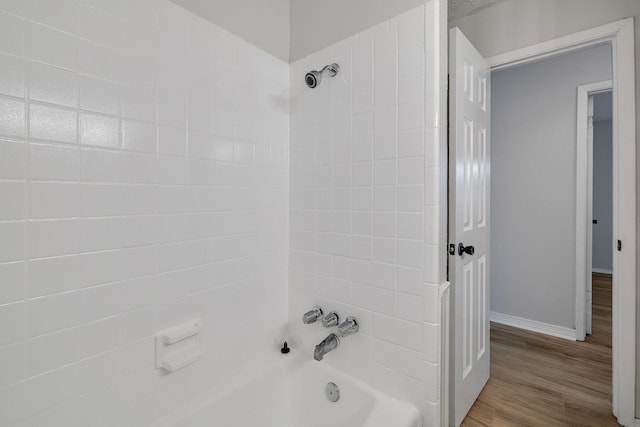 bathroom with hardwood / wood-style flooring and tiled shower / bath combo