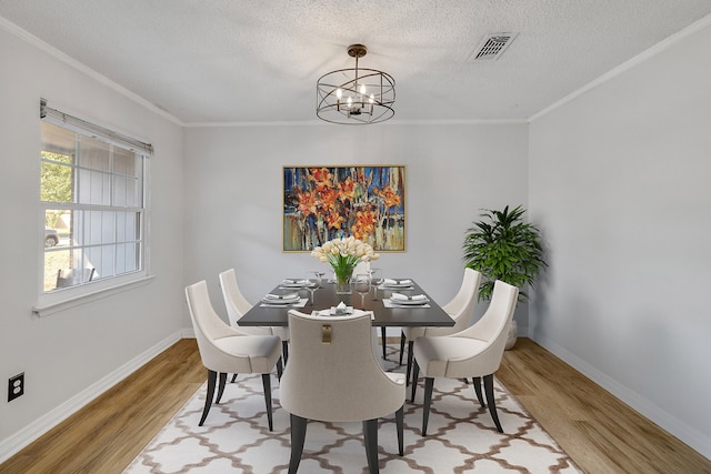 dining space featuring a textured ceiling, hardwood / wood-style floors, a notable chandelier, and ornamental molding