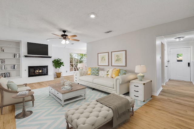 living room featuring a fireplace, a textured ceiling, and light hardwood / wood-style flooring