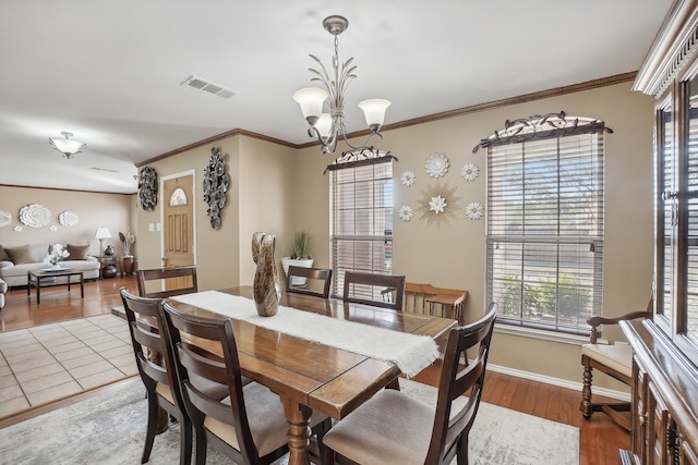 dining room with an inviting chandelier, wood-type flooring, and crown molding