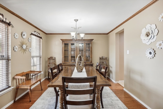 dining area with ornamental molding, a chandelier, and hardwood / wood-style flooring