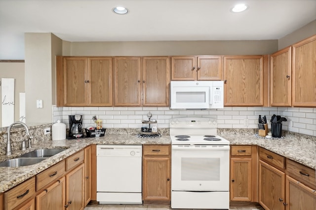 kitchen featuring sink, decorative backsplash, light stone counters, and white appliances