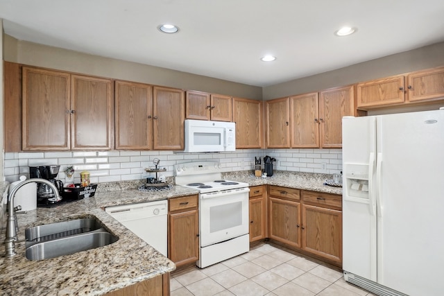 kitchen featuring decorative backsplash, light stone countertops, light tile patterned flooring, sink, and white appliances