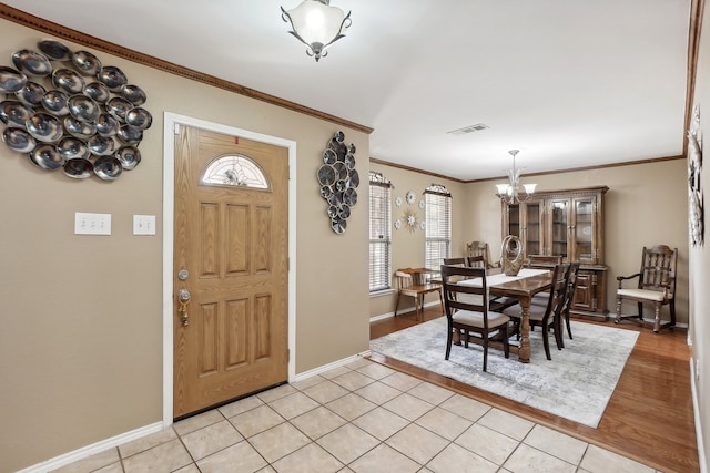 foyer entrance featuring light hardwood / wood-style floors, ornamental molding, and a chandelier