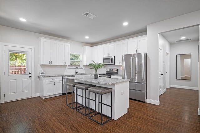 kitchen featuring appliances with stainless steel finishes, white cabinets, a wealth of natural light, and a kitchen island