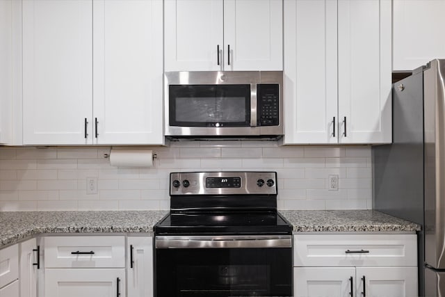 kitchen featuring light stone countertops, decorative backsplash, appliances with stainless steel finishes, and white cabinets