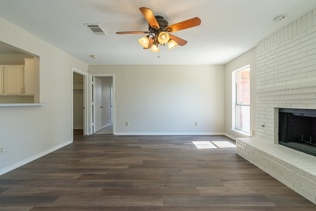 unfurnished living room with a brick fireplace, ceiling fan, and dark hardwood / wood-style flooring