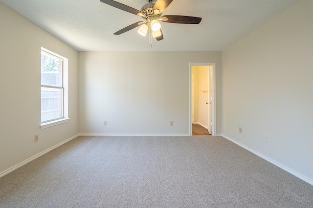 spare room featuring a textured ceiling, light colored carpet, and ceiling fan