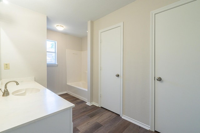 bathroom featuring vanity, wood finished floors, baseboards, and shower / tub combination