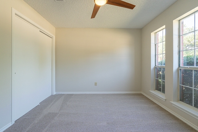 unfurnished room featuring a textured ceiling, carpet floors, and ceiling fan