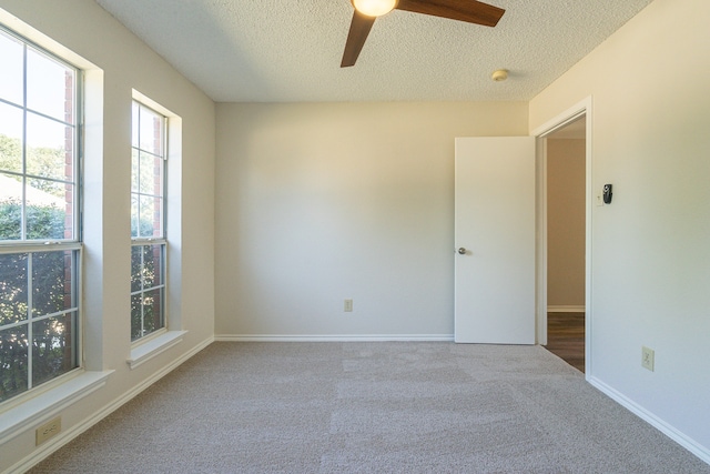 carpeted empty room with ceiling fan and a textured ceiling