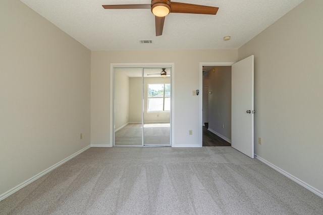 unfurnished bedroom featuring a closet, ceiling fan, light carpet, and a textured ceiling