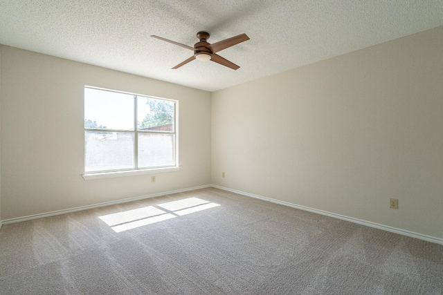 carpeted spare room with a ceiling fan, baseboards, and a textured ceiling