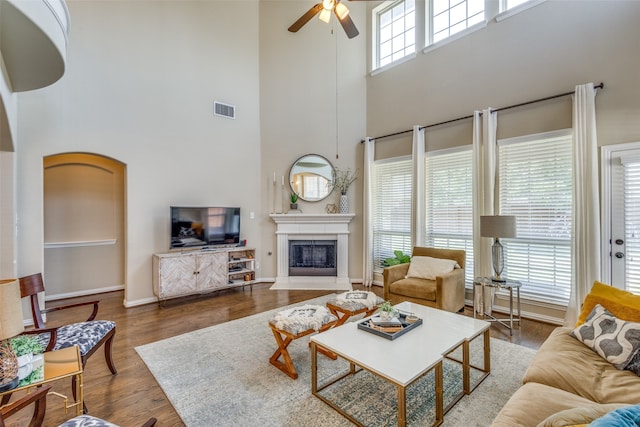 living room featuring a towering ceiling, wood-type flooring, and ceiling fan