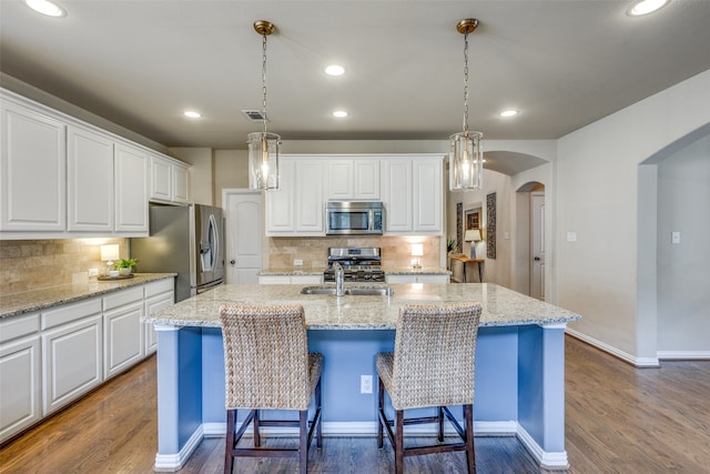 kitchen featuring white cabinets, stainless steel appliances, dark wood-type flooring, and a kitchen island with sink